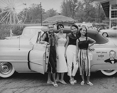 Young ladies pose with a vehicle owned by popular radio DJ, Charles 