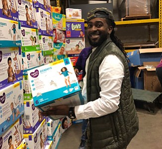 Troy Brown holding a box of diapers during the event.