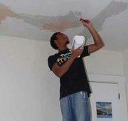 A volunteer repairs the ceiling. 