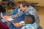 AARP Experience Corps volunteer member Doug Hebard reads to eight-year-old Raymond Bowman and seven years-old Tyon Matthews.  