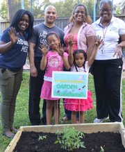 The new gardeners proudly display their soil-covered hands as they christen their garden along with, from left, Stephanie Purnell of Howard, their father, Antonio Evans, mother, Michelle Phillips-Evans, and Dr. Michal Young of Howard University College of Medicine and Howard University Hospital.  
