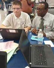 (Right) Patterson High School student Brian Clark demonstrates some of the applications he created to Patterson High School Science Teacher Dr. Ethelbert Ekeocha.                                                                                                                                           