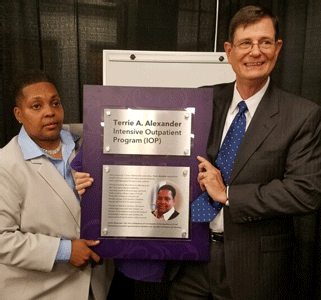 Terrie A. Alexander with Dr. Steven Hursh, president of the Institutes for Behavior Resources, holding the plaque naming the Intensive Outpatient Program after Terrie, which will hang outside the program’s doors.
