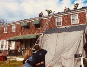 Employees from Superior Design & Restoration work on the roof as Stacia Evans and Keith Randlett look on.