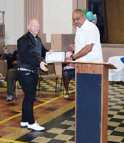 Walter Billups of NCIA (National Center on Institutions and Alternatives) presents Carlton Boyce with his graduate t certification.